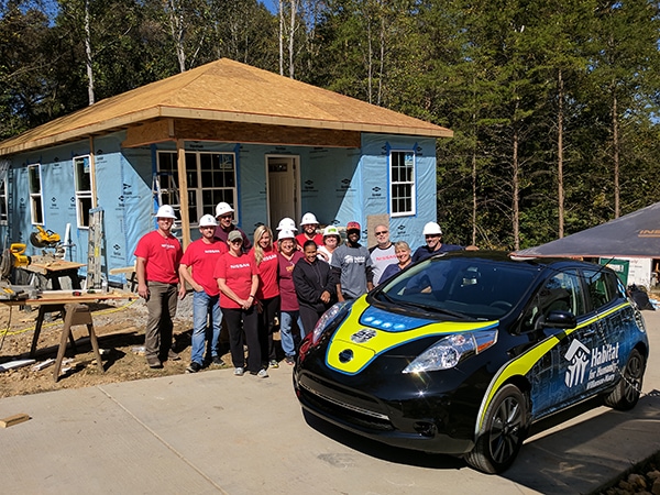 Nissan volunteer team next to the new Nissan Leaf with custom wrap. - 12-Point SignWorks - Franklin, TN