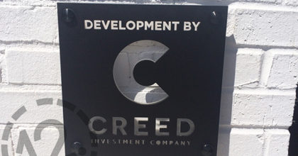 The Creed Investment Company exterior logo sign installed on painted brick in the Gulch in Nashville. 12-Point SignWorks - Franklin TN