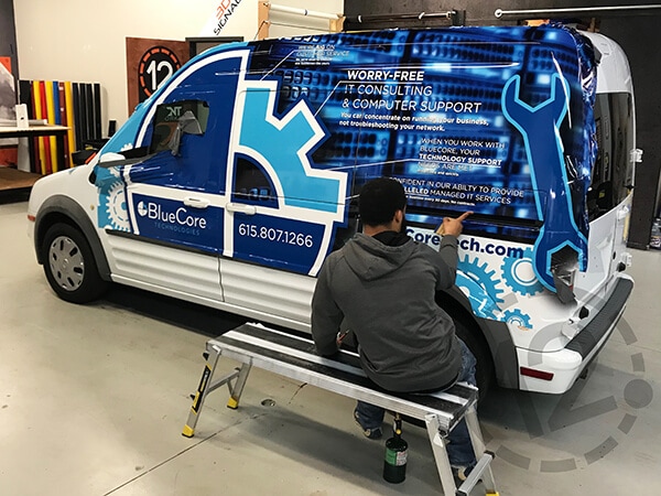 Carefully Applying BlueCore Technologies' Custom Van Wrap. 12-Point SignWorks - Franklin, TN